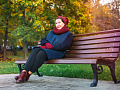 smiling woman sitting on a park bench on an autumn day
